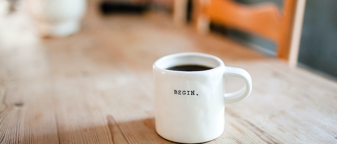 coffee mug with the word "begin" on a wooden table