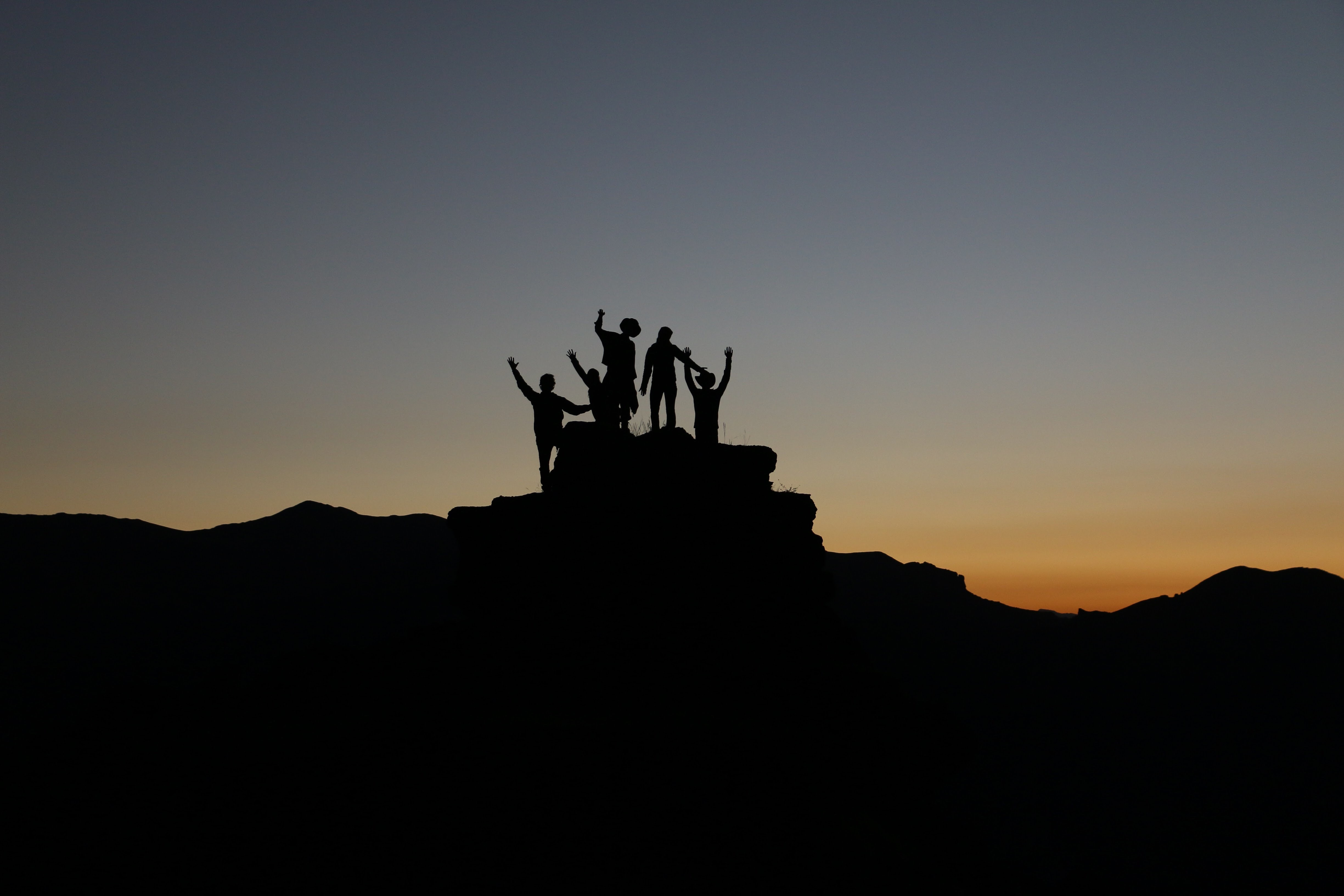 group of people watching the sunrise after climbing a rock